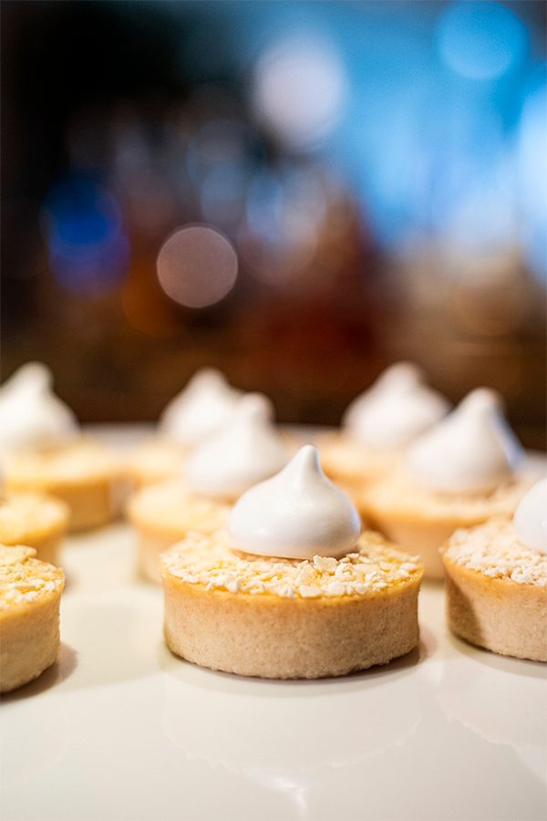 Close-up of a plate of small tropical fruit tarts topped with meringue. 